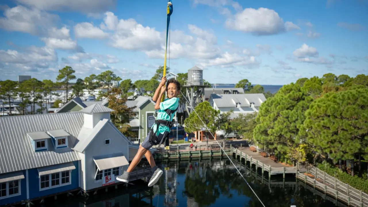 Kids ziplining over the lagoon at Baytowne Adventure Zone in the Village of Baytowne Wharf